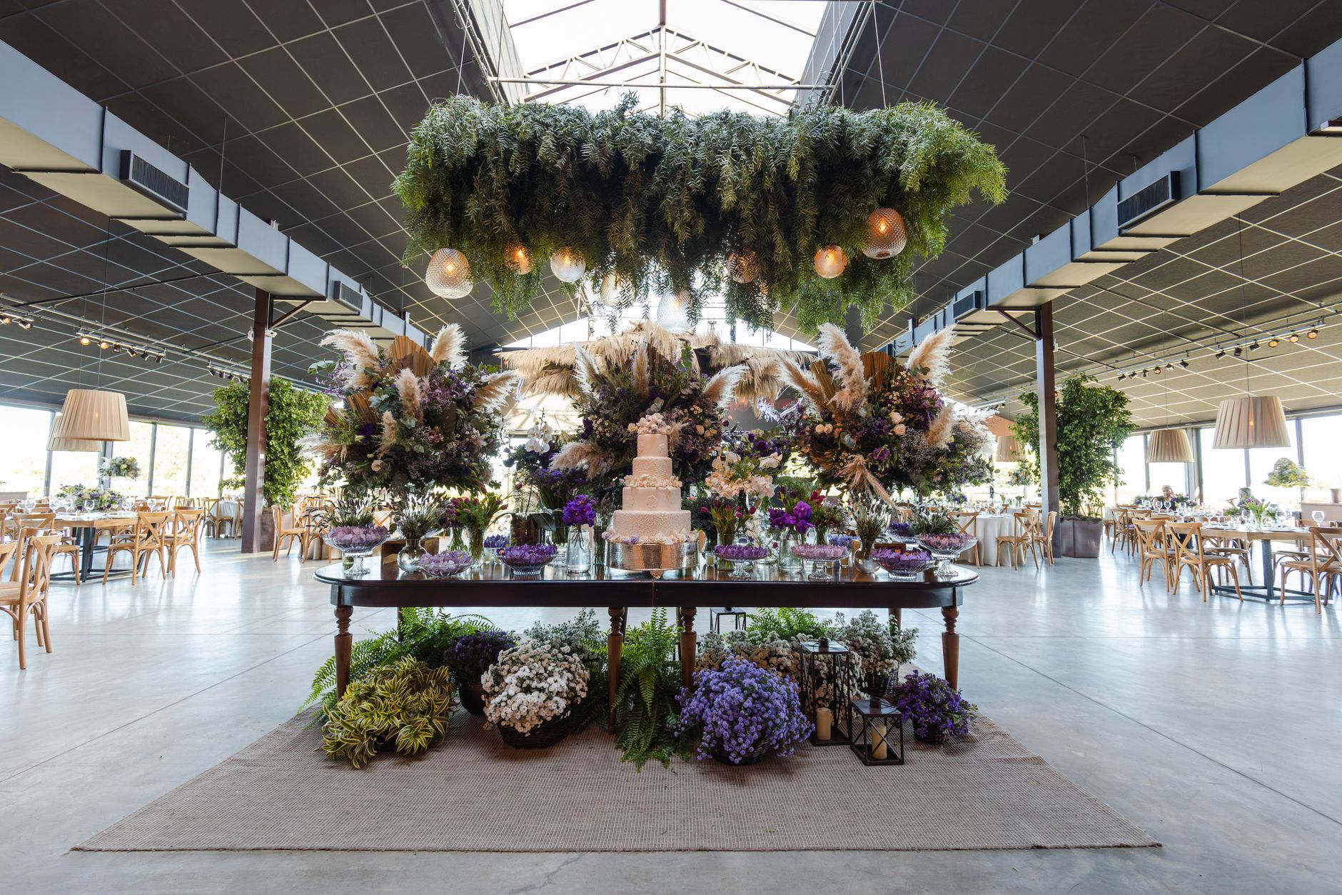 Stunning indoor wedding venue with floral arrangements and a multi-tiered cake on a decorated table. — App E Siti Web Pericol
