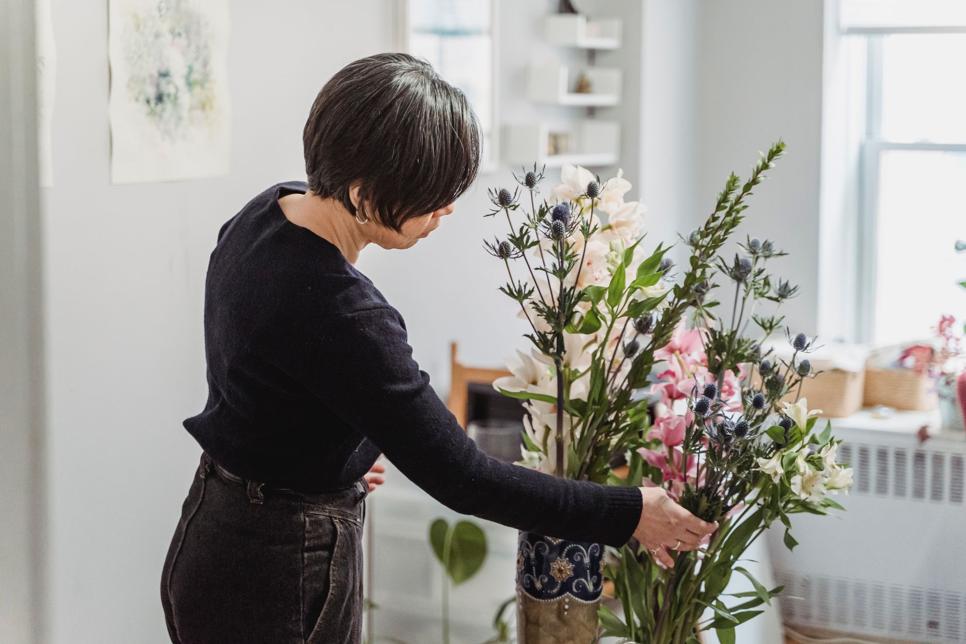 A woman carefully arranges a vibrant floral display in a well-lit home setting. — Sick Of Tinder And Bumble? Try These Ne
