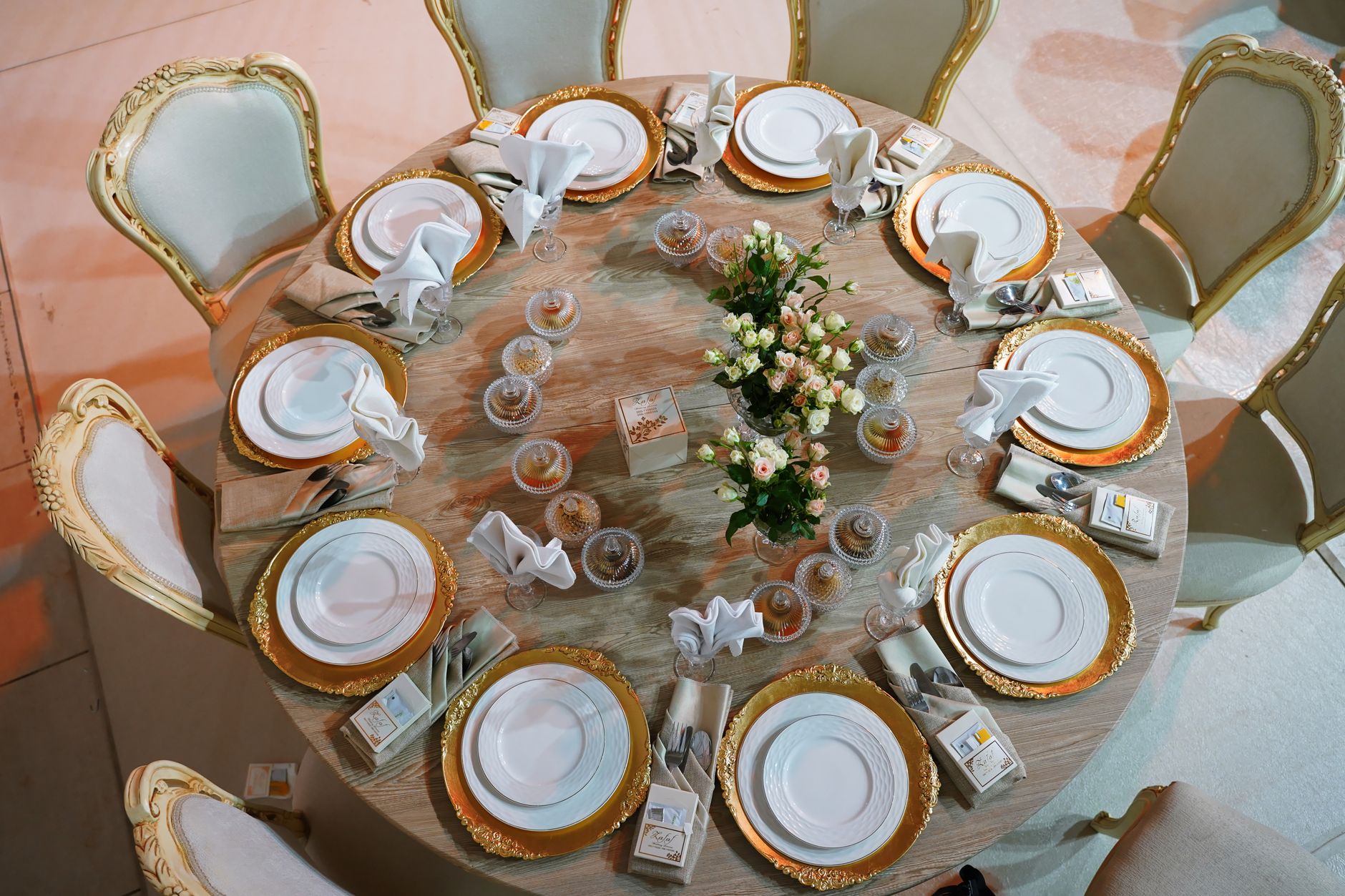Luxurious round table with golden plates and roses, meticulously set for a wedding celebration. — Los Mejores Videochats Y Ap